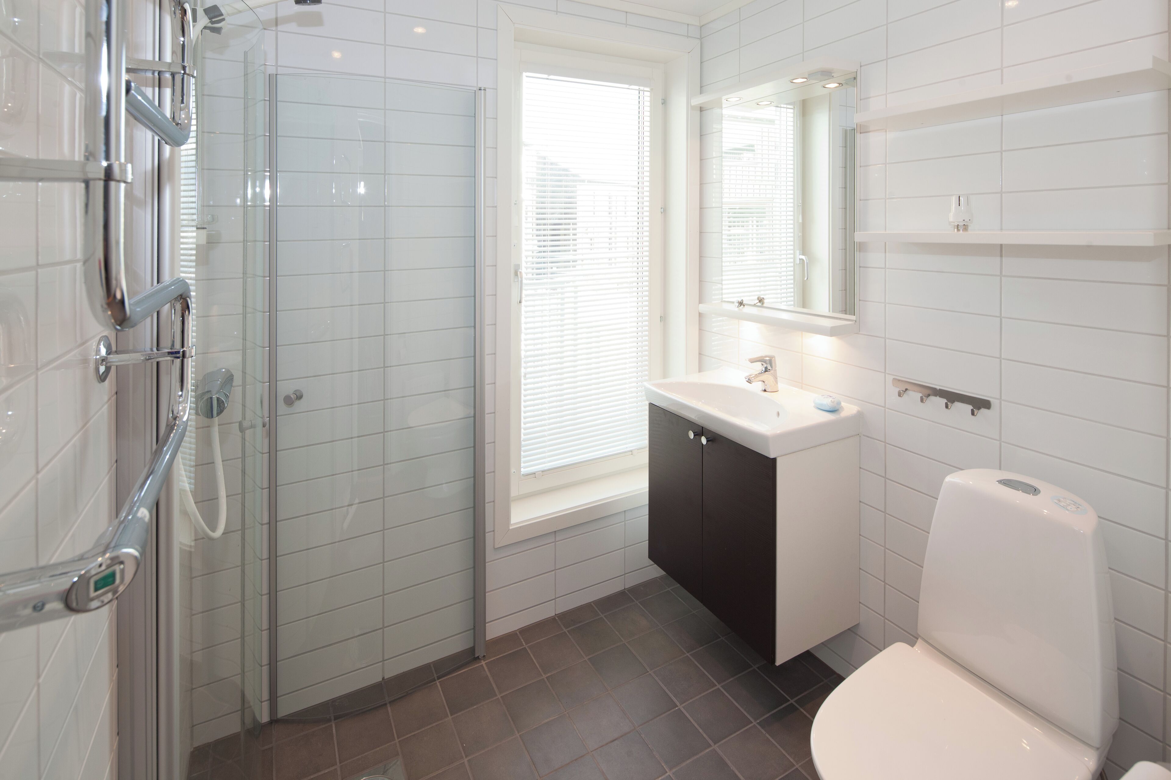Une salle de bain moderne avec une douche à parois de verre, un lavabo blanc avec un miroir au-dessus et des toilettes blanches.