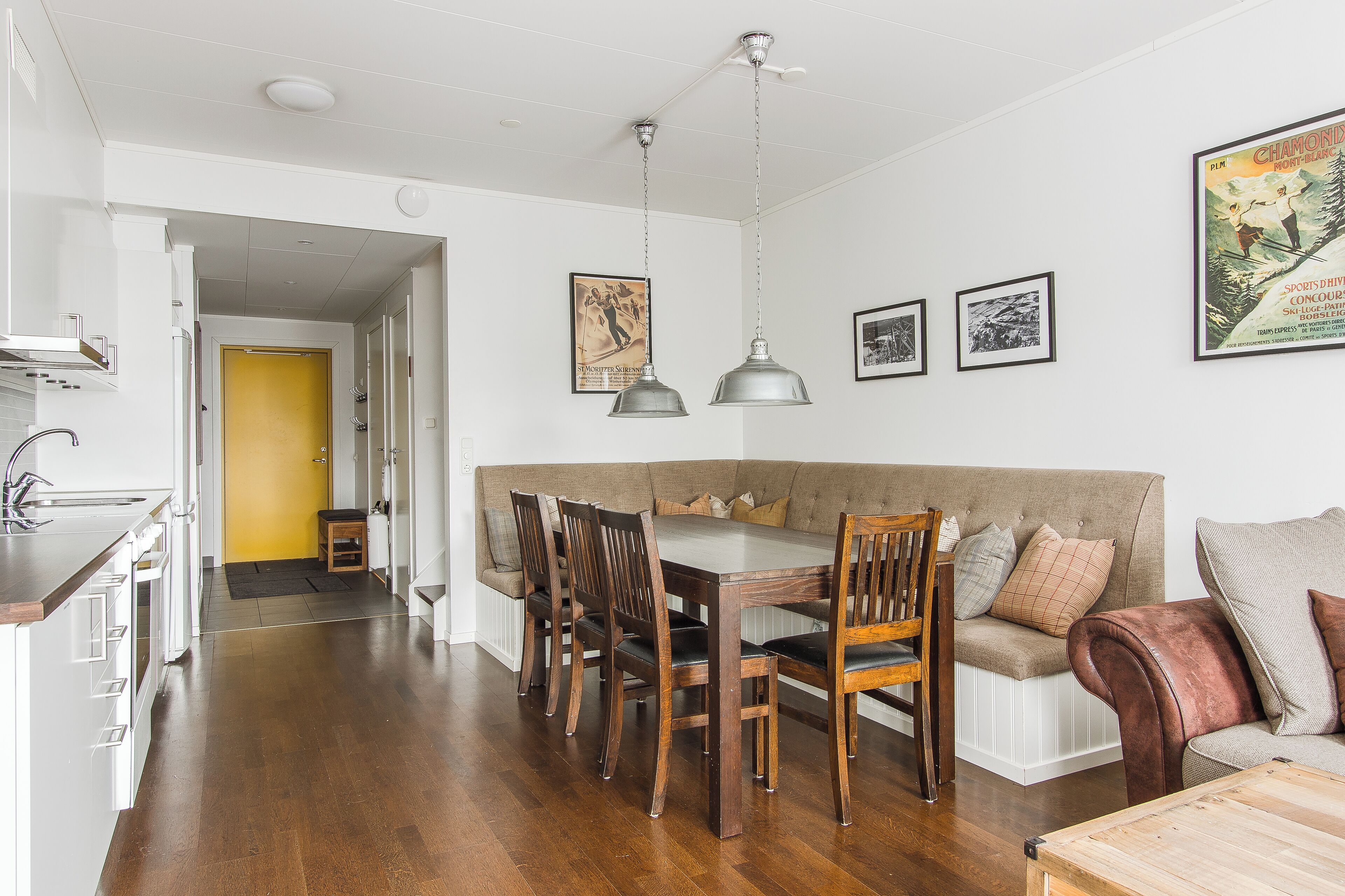 Una cucina moderna con mobili bianchi, un tavolo da pranzo in legno e una panca con sedie integrata.