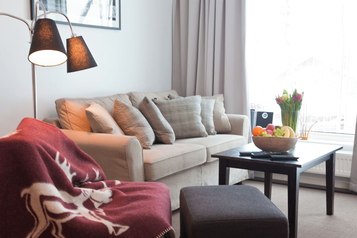 Ein Wohnzimmer mit einer Couch, einem Hocker und einem Couchtisch mit Obstschale.