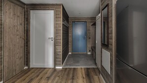 Una cocina moderna con un refrigerador de acero inoxidable, paneles de madera en las paredes y una puerta azul al fondo.