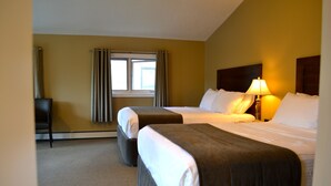 A hotel room with two beds, a window with curtains, a lamp, and a chair. - A Good Nite's Rest Bed and Breakfast (Banff)