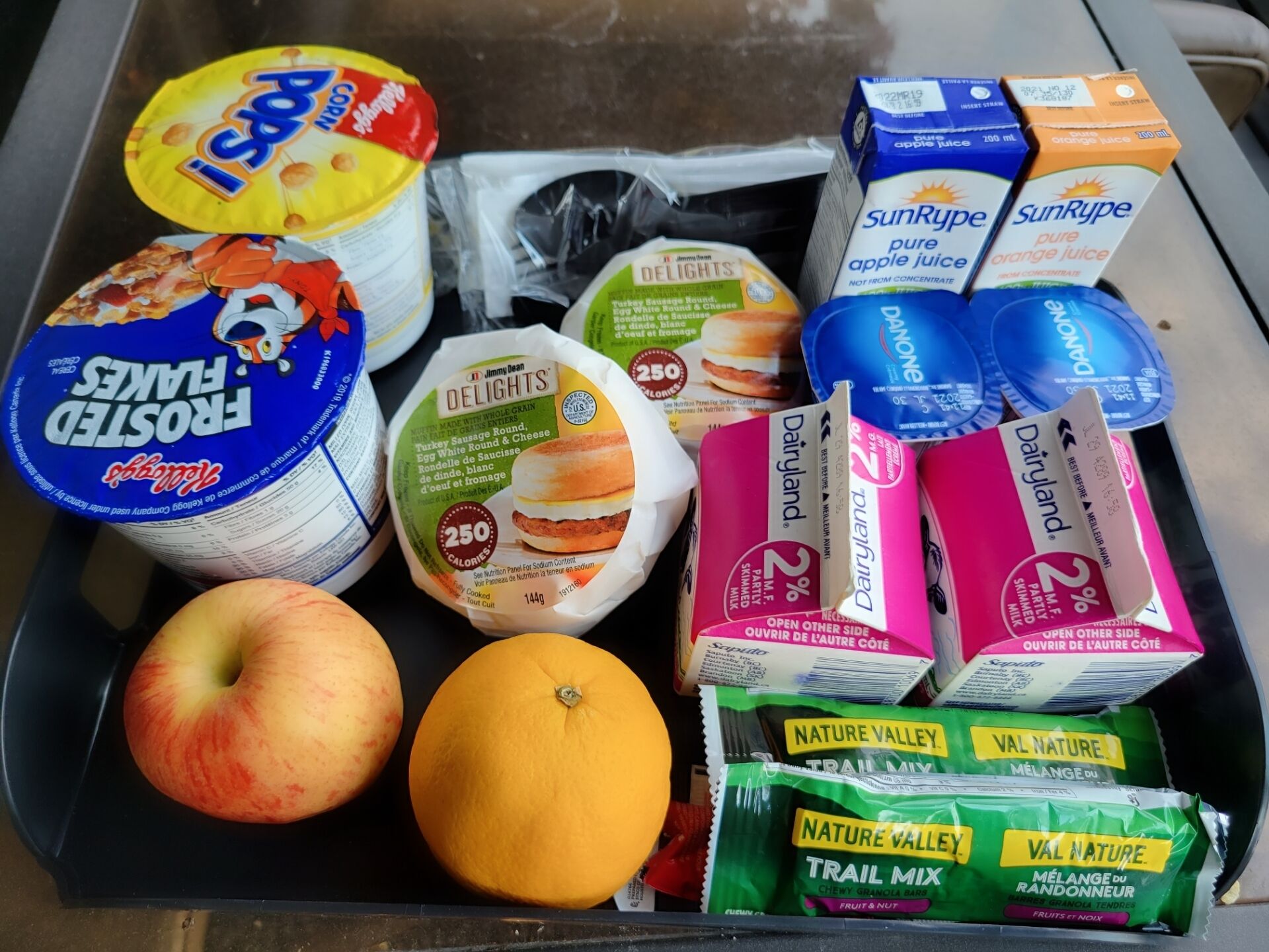 Variedad de alimentos, incluyendo yogur, jugo y aperitivos, en un refrigerador.