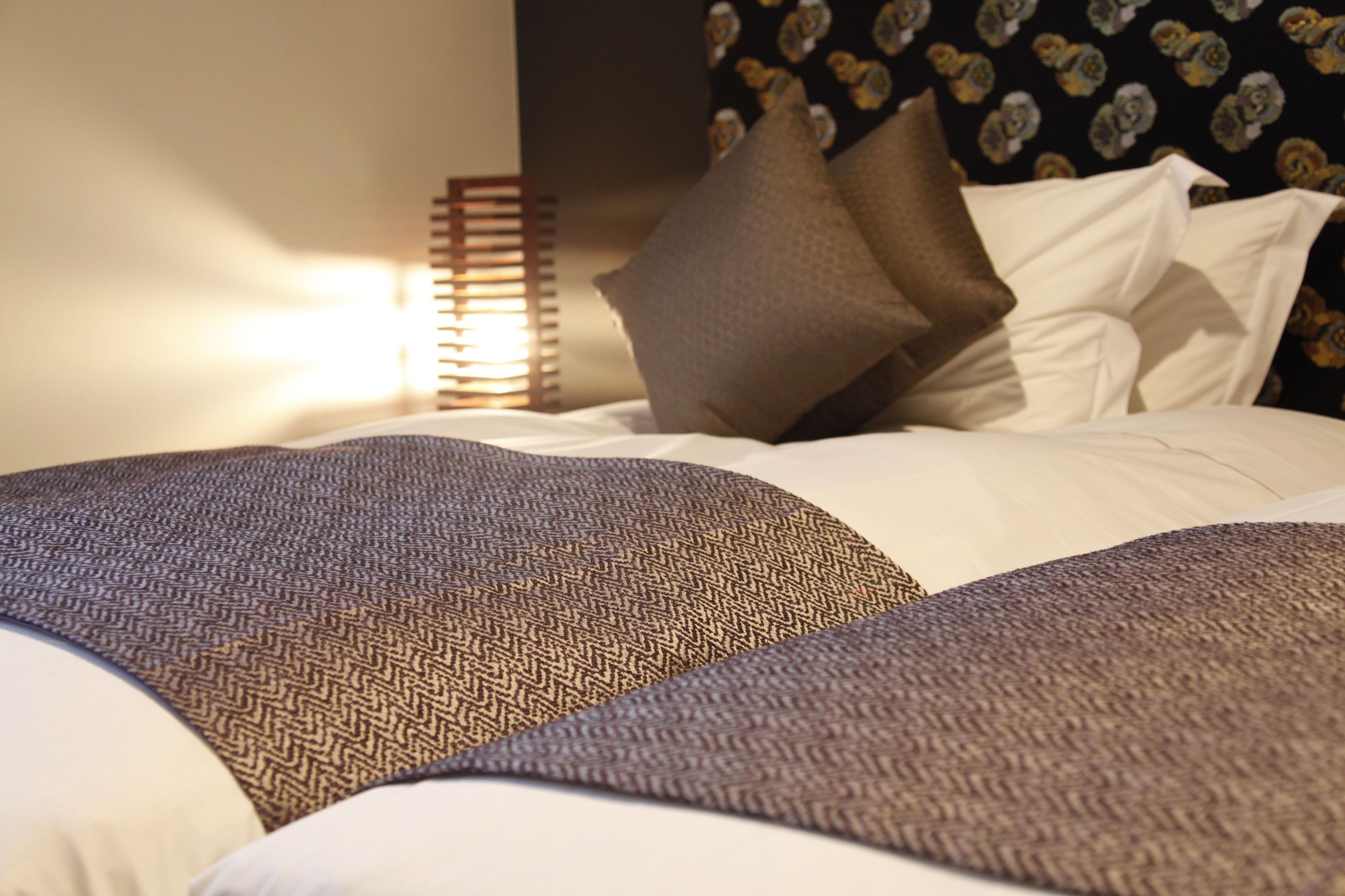 A neatly made bed with patterned pillows and a headboard with a floral design.