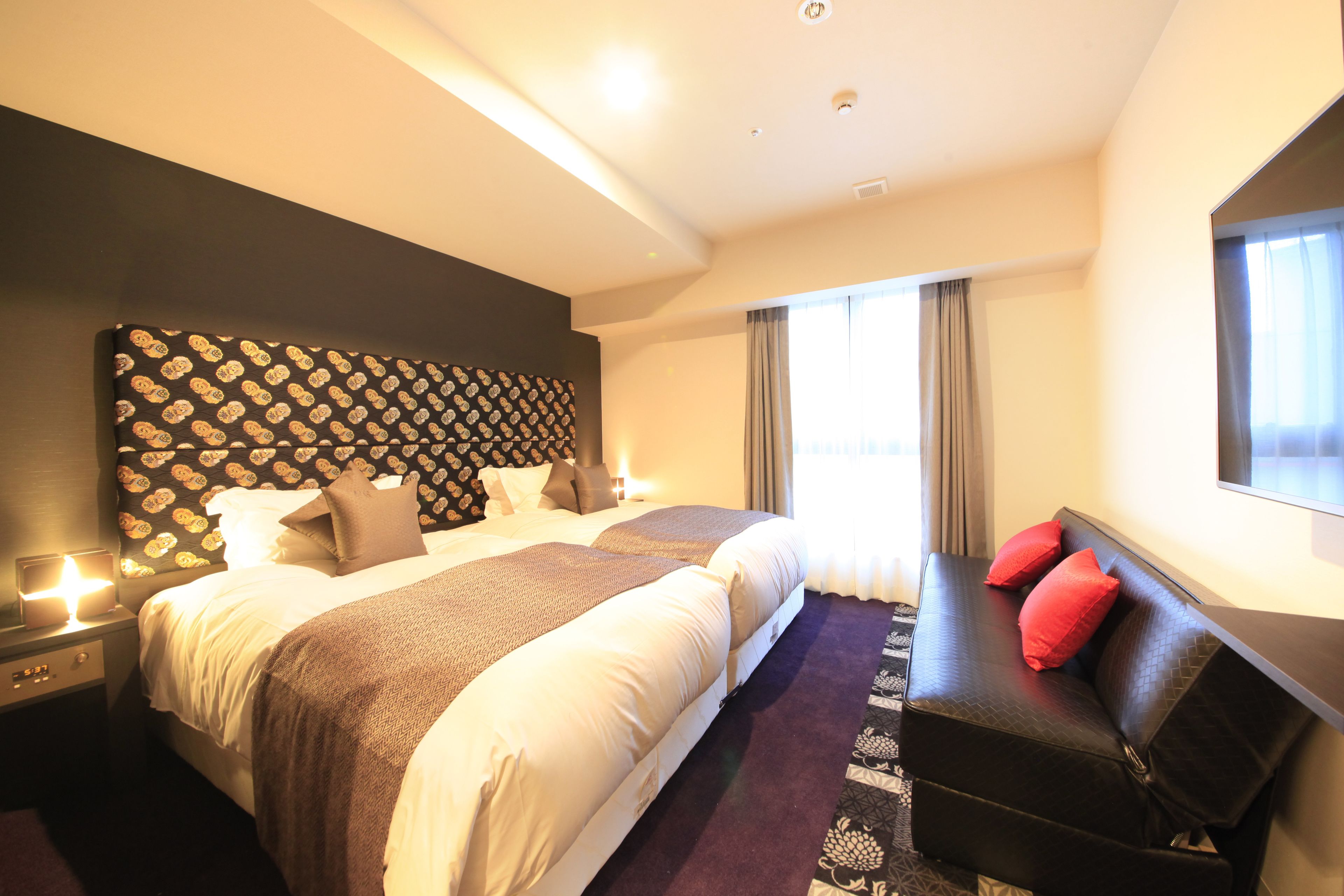 Una habitación de hotel moderna con una cama grande, un sofá y una televisión.