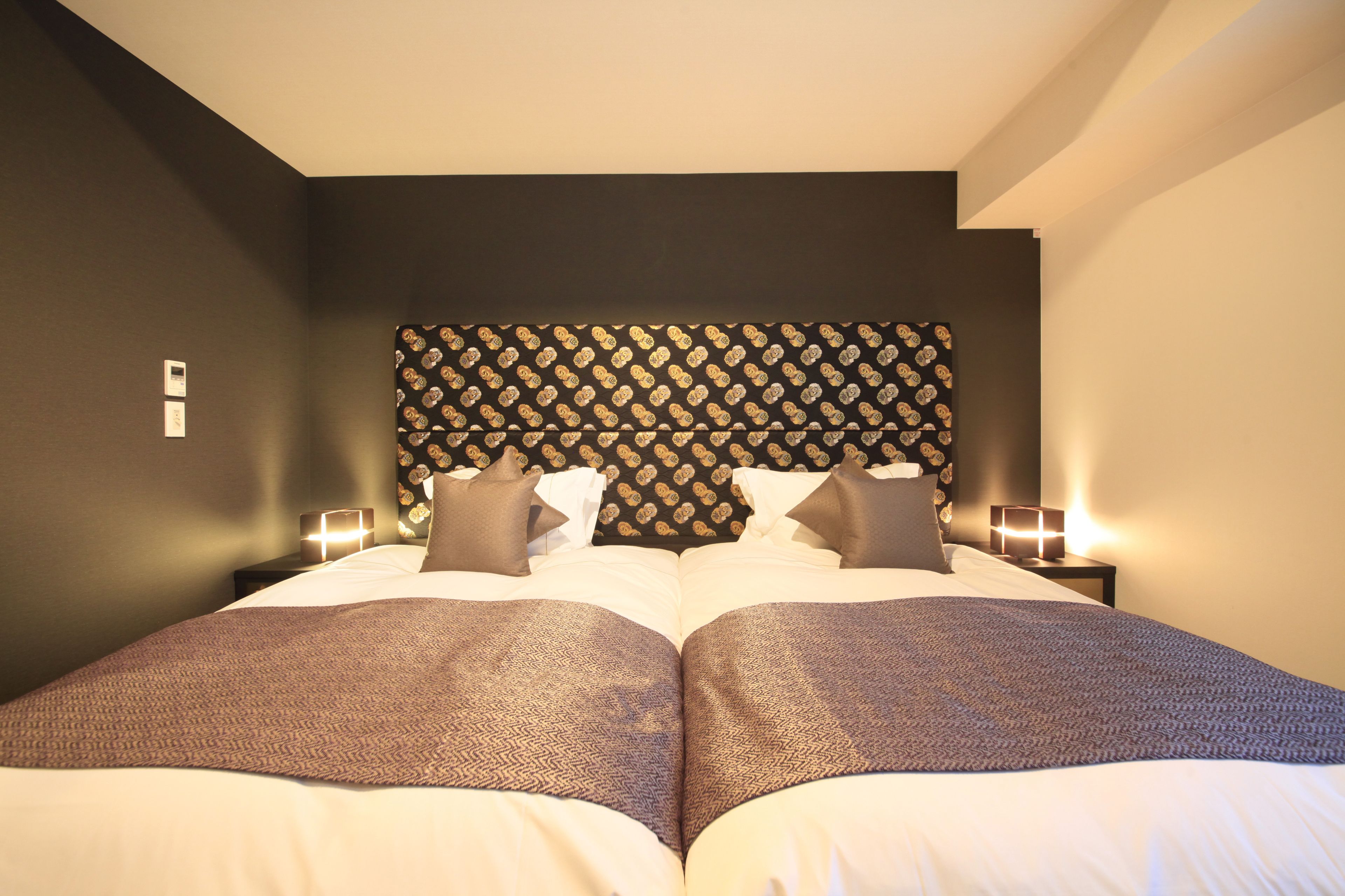A double bed with a patterned headboard, two bedside tables with lamps, and a neutral color scheme.