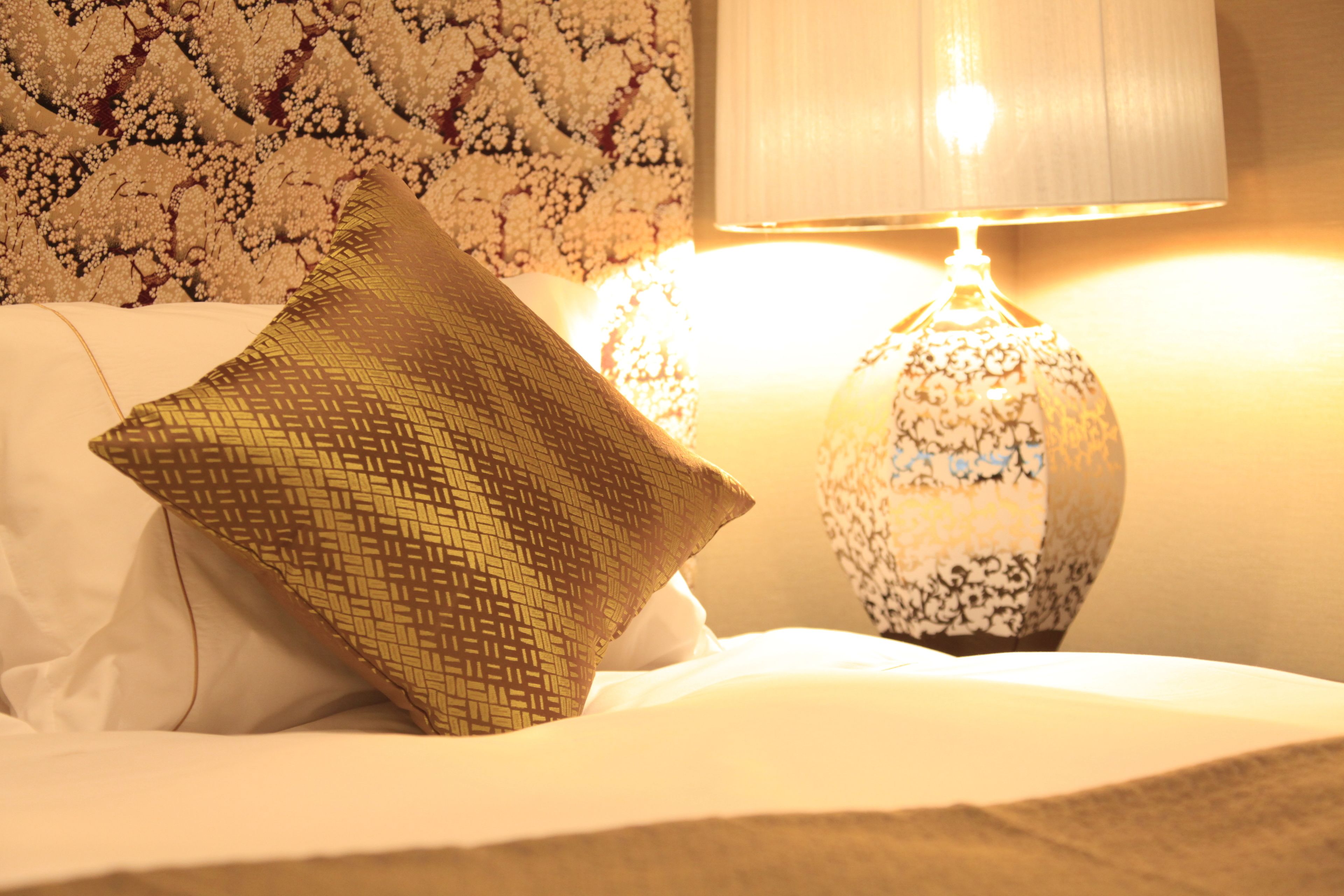 Un letto con un cuscino fantasia e una lampada decorativa.