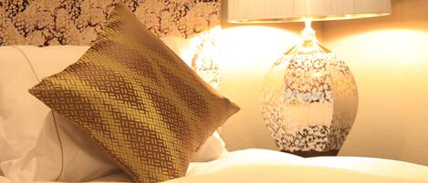 A bed with a patterned pillow and a decorative lamp.