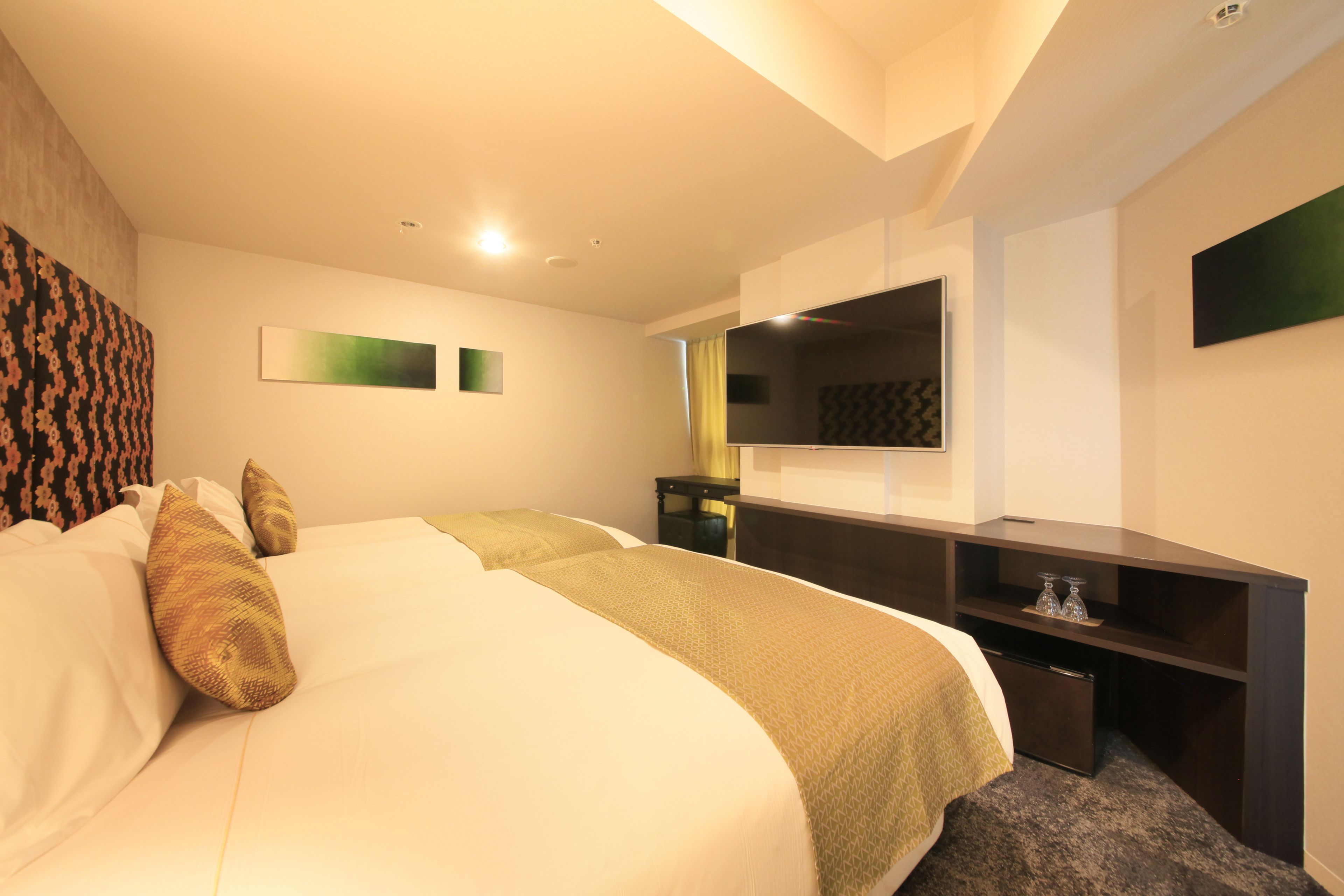 A hotel room with two beds, a desk, a flat-screen TV, and a mirror.