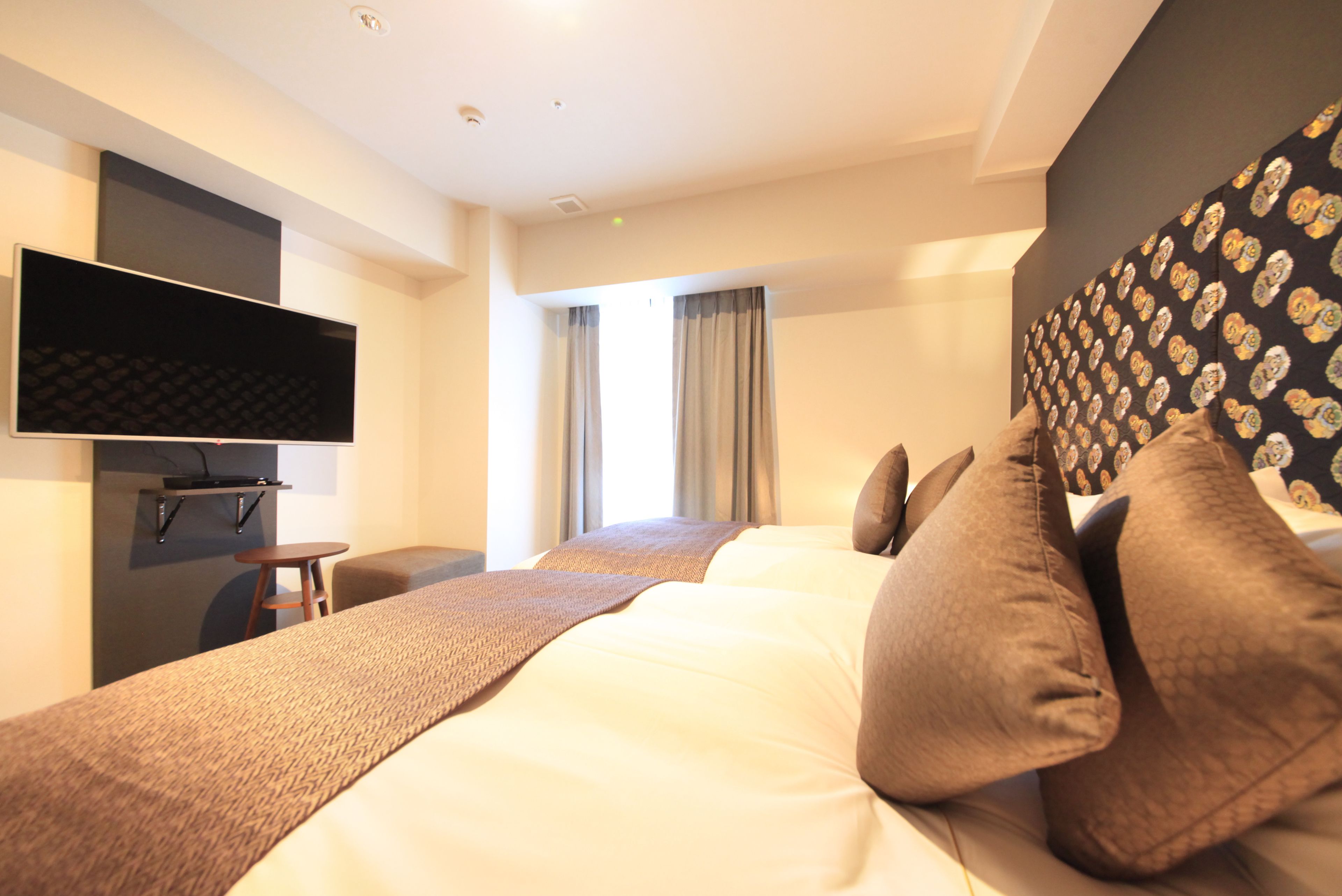 Une chambre d’hôtel avec un grand lit, un téléviseur à écran plat fixé au mur, une petite table et une chaise.