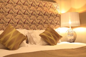 A bed with white bedding and two patterned pillows, a patterned headboard, and a lamp with a white shade. - Centurion Hotel Ikebukuro (Tokyo)