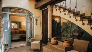 A lobby with wicker furniture, a staircase, and a mirror. - Casa Florida (San Miguel de Allende)