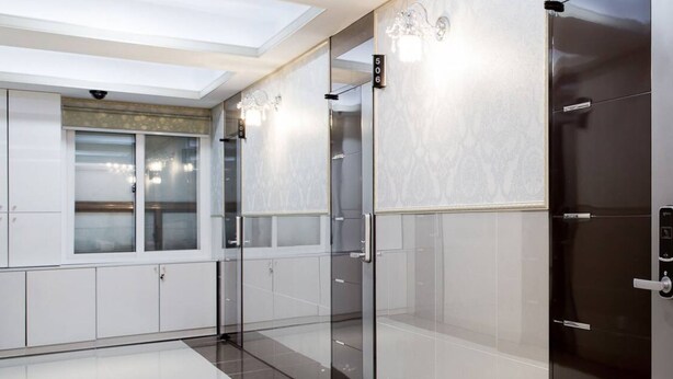 A modern elevator with glass doors, a marble wall, and a number sign indicating the floor. - Hostel Chloe (Seoul)