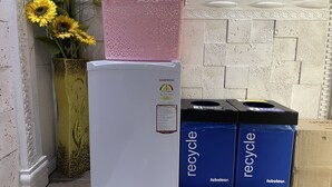 A white refrigerator with a pink basket on top, next to two blue recycling bins labeled 'fabulous'. - Hostel Chloe (Seoul)