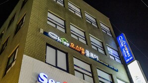 A multi-story building with various signs, including a prominent 'Seafood' sign and a 'Cafe' sign. - Hostel Chloe (Seoul)