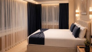 A modern hotel bedroom with a large bed, a chandelier, and sheer curtains. - Burçman Hotel (Bursa)