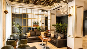A modern living room with a sectional sofa, a coffee table, and a dining area with chairs and a table. - Burçman Hotel (Bursa)