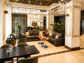 A modern living room with a sectional sofa, a coffee table, and a dining area with chairs and a table. - Burçman Hotel (Bursa)