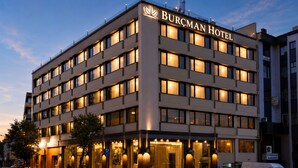 A multi-story hotel with a prominent sign, large windows, and a parking area. - Burçman Hotel (Bursa)