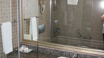 A bathroom with a sink, mirror, shower, and tiled walls.