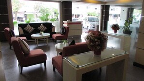Un vestíbulo moderno con sofá, sillas, una mesa de centro y un jarrón de flores.