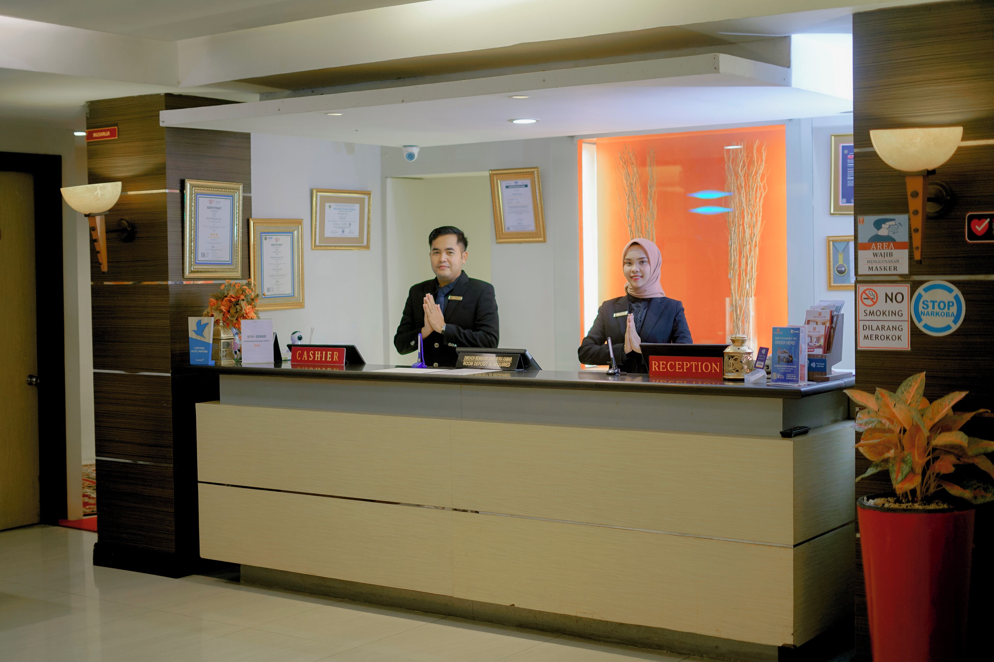 A reception desk with framed certificates on the wall, a reception sign, and a no-smoking sign.