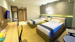 Habitación de hotel con dos camas, un escritorio, una silla, un televisor y un armario.