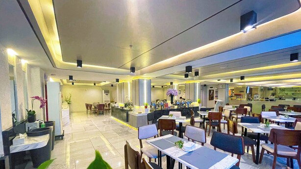 Un restaurante moderno con barra, varias mesas y sillas para comer.