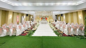 Una habitación de hotel con una mesa larga, sillas y una alfombra verde.