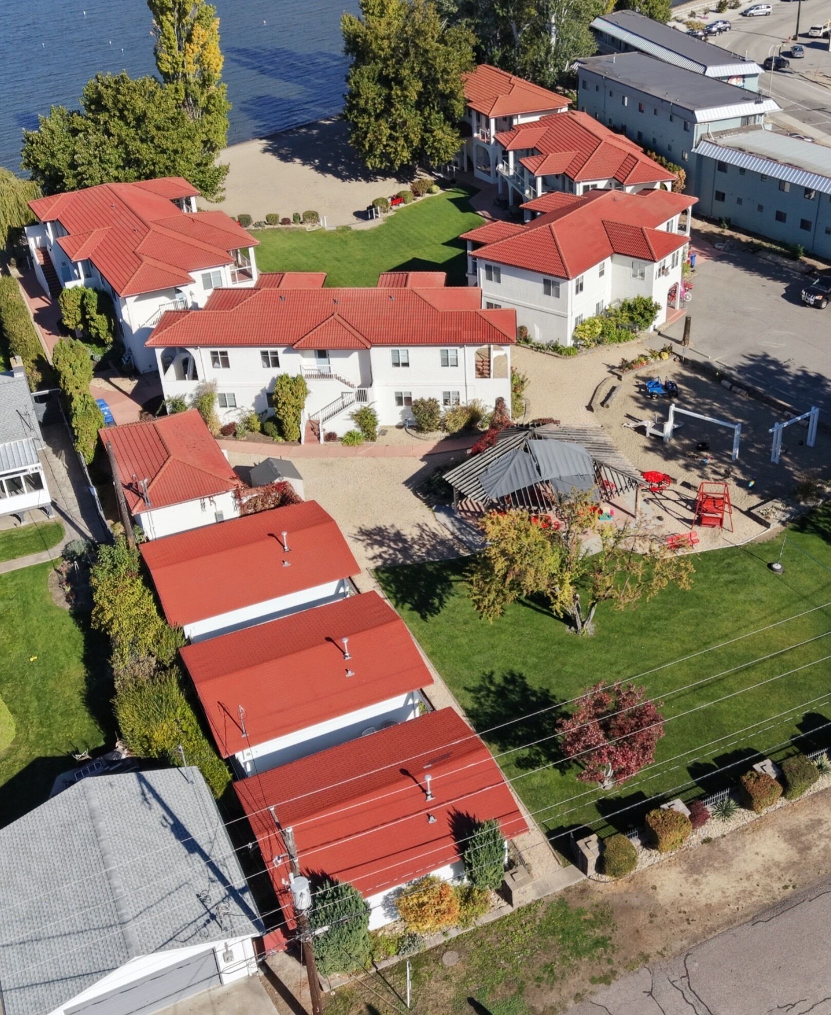 A residential area with multiple houses, a playground, and a body of water in the background.