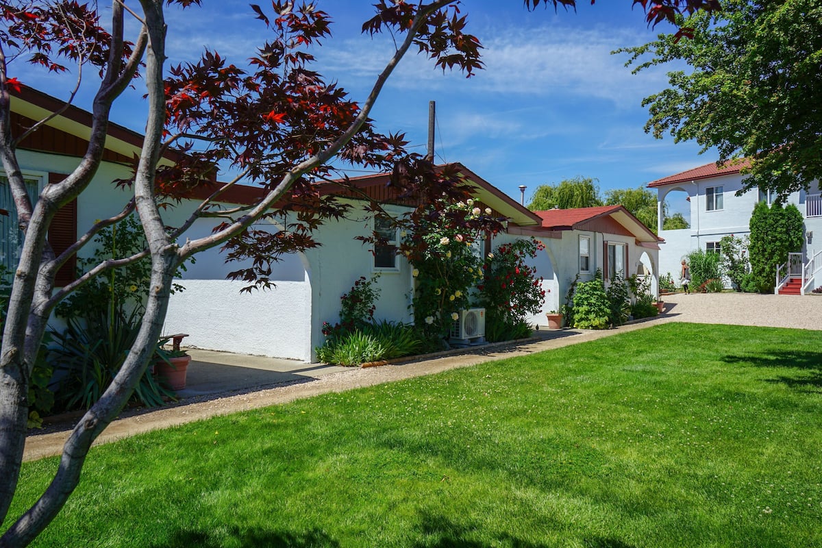 A residential area with a white house, a red roof, and a well-maintained lawn.