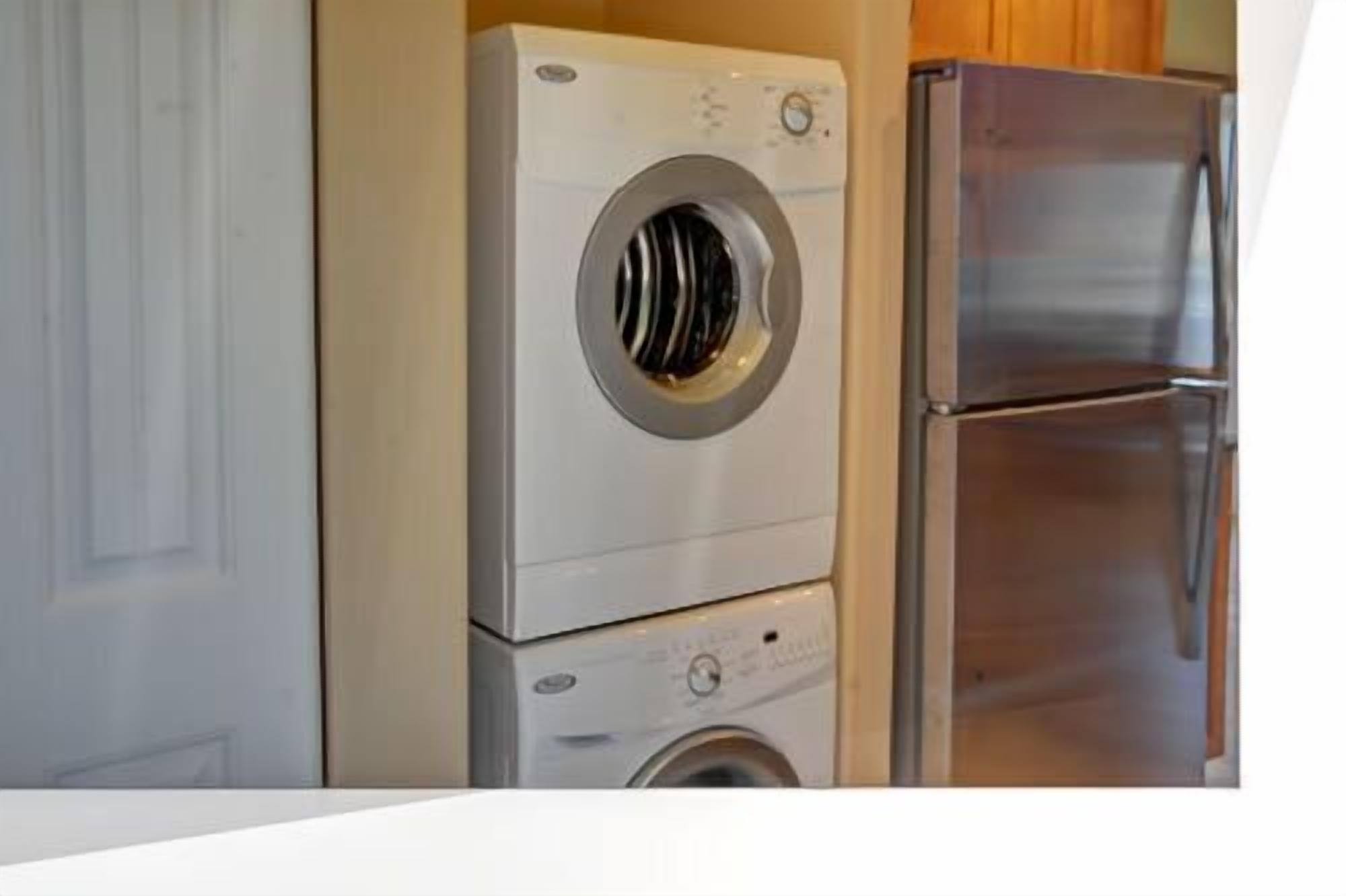 Una lavadora y secadora compactas en una cocina con un refrigerador de acero inoxidable.
