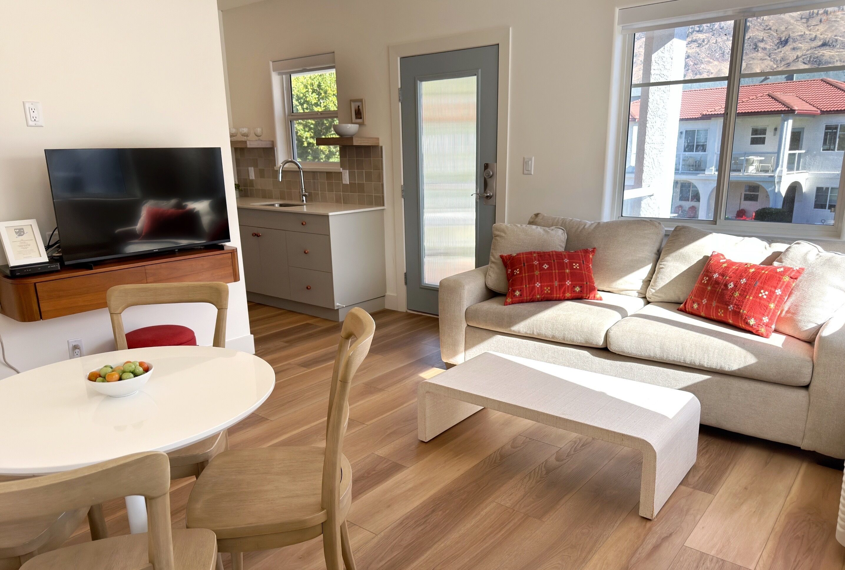 Una sala de estar moderna con un sofá, televisión, mesa de comedor y una zona de cocina.