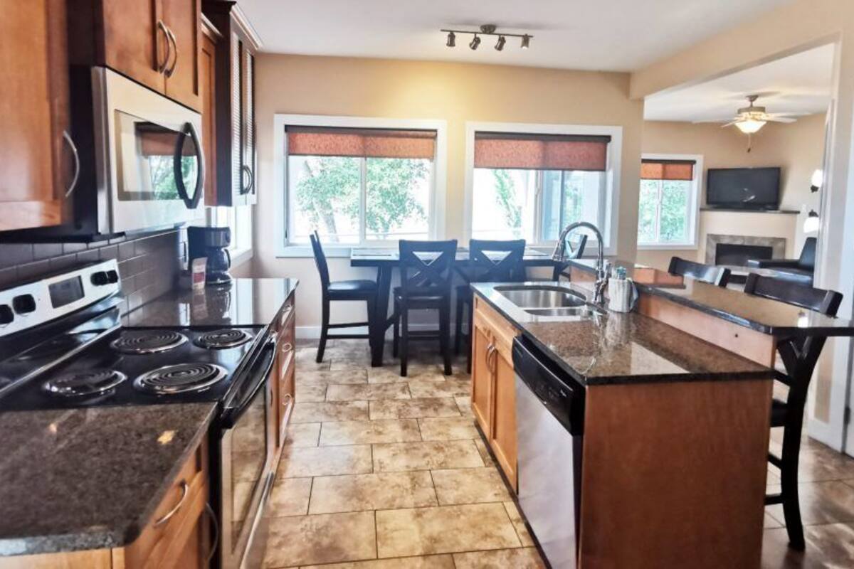 A kitchen with a stove, oven, microwave, and a dining area with chairs and a table.