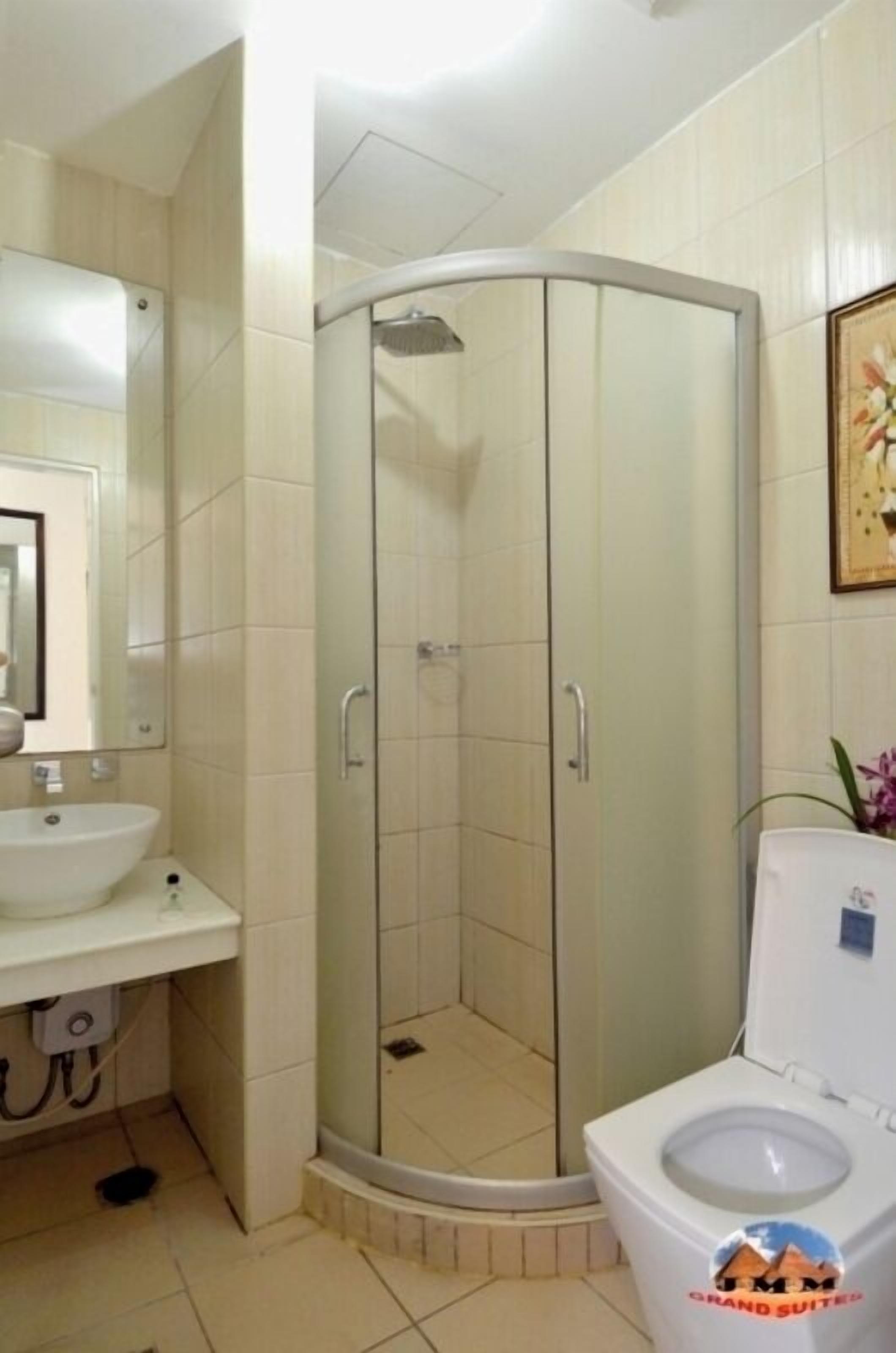 A bathroom with a shower enclosure, a sink, and a toilet.