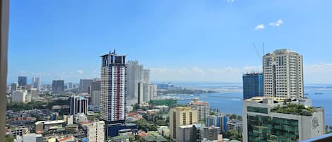 A cityscape with a variety of buildings, including high-rise residential and commercial structures, and a body of water in the background.