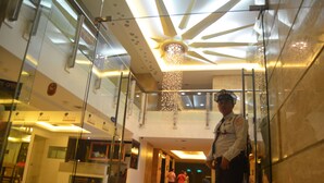 Una hall con soffitto in vetro, un addetto alla sicurezza e alcune persone sullo sfondo.