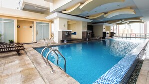 Piscina interna con acqua cristallina e blu, circondata da una pavimentazione piastrellata e da panchine.