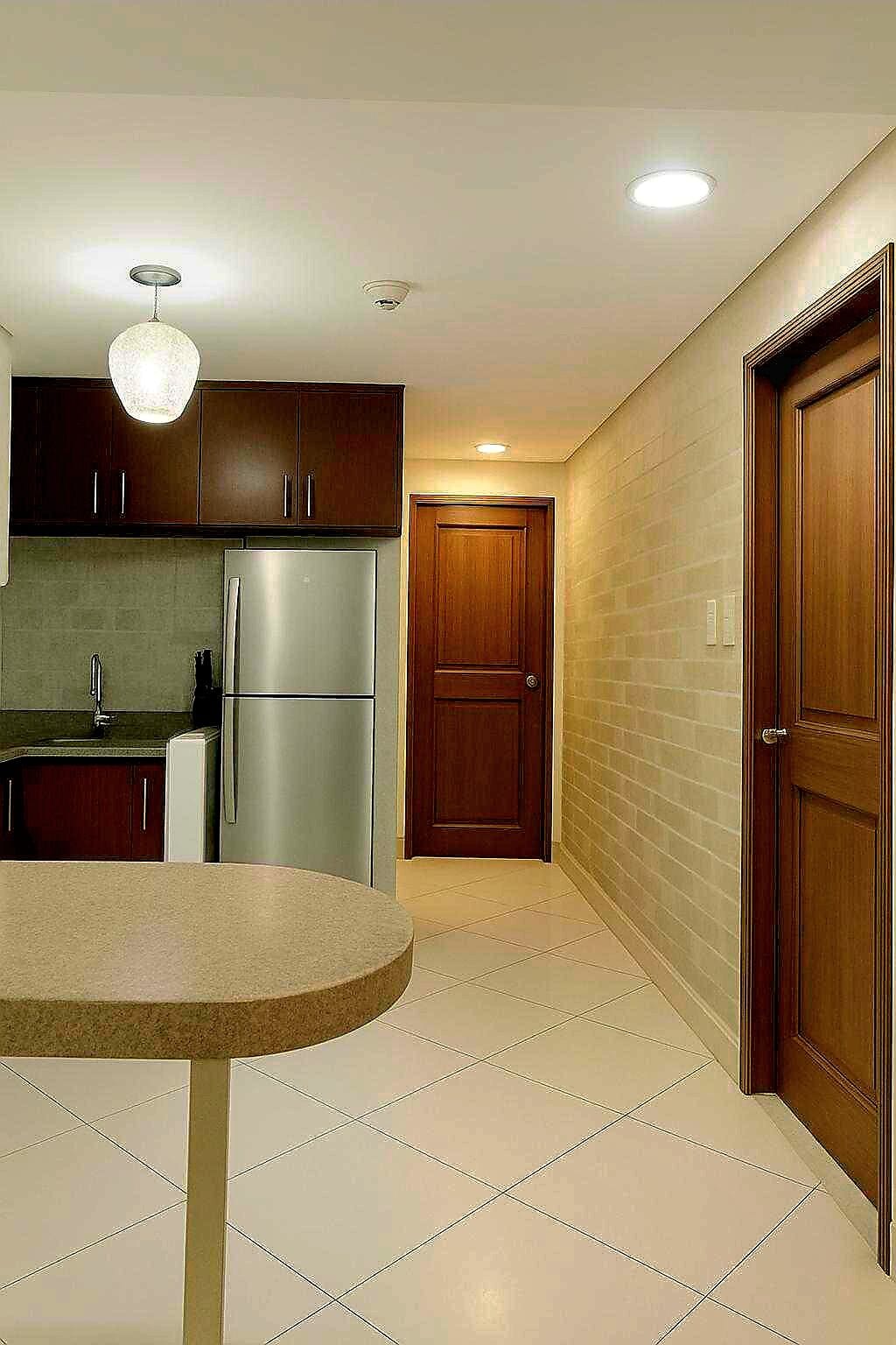 A modern kitchen with dark wooden cabinets, stainless steel appliances, and a round island.