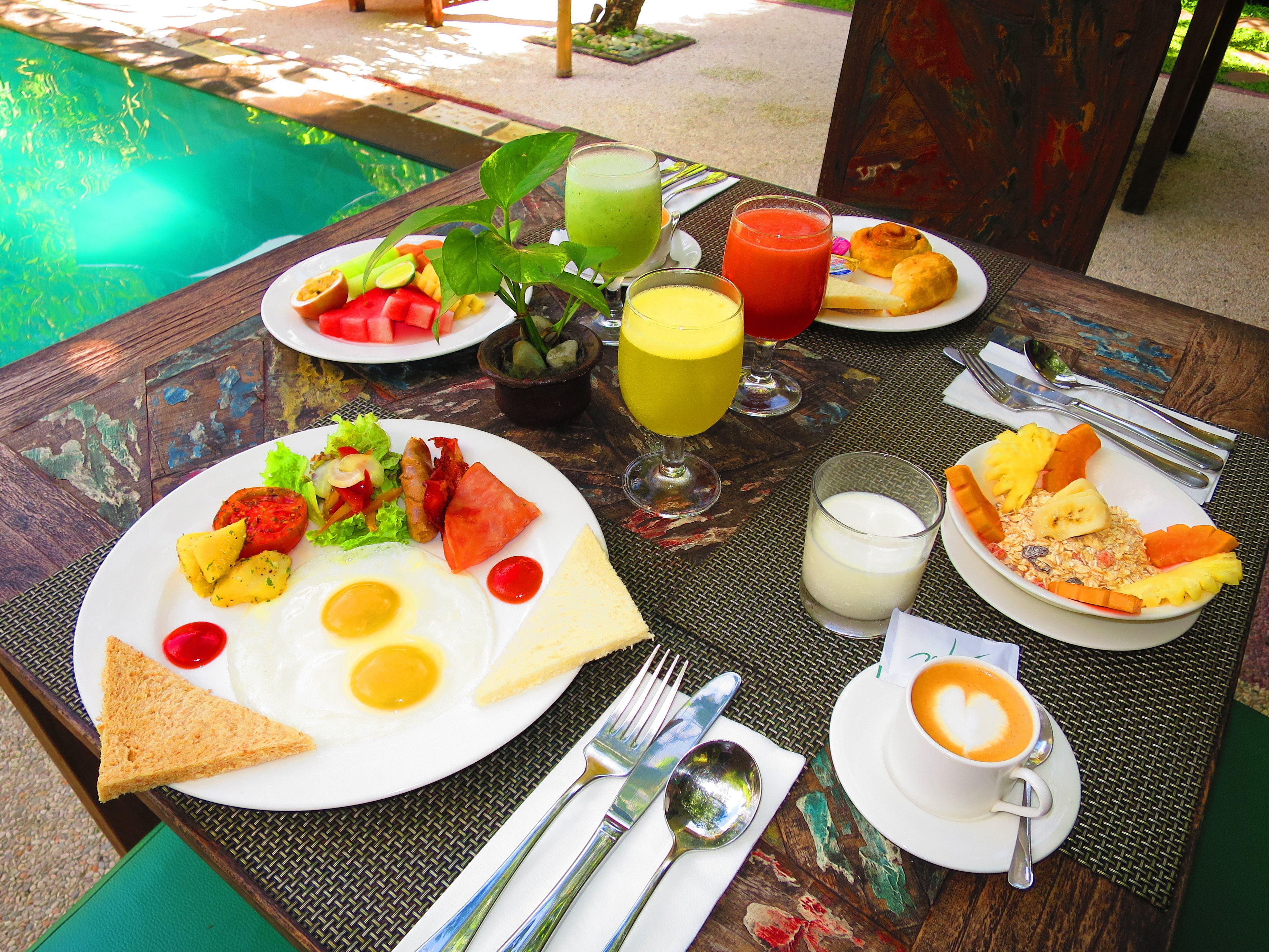 A breakfast table with plates of food, drinks, and a cup of coffee.