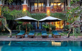 Una piscina al aire libre, sombrillas, sillones reclinables de piscina