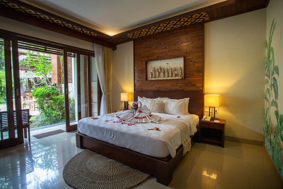 A large bed with a white bedspread, two bedside lamps, and a wooden headboard.