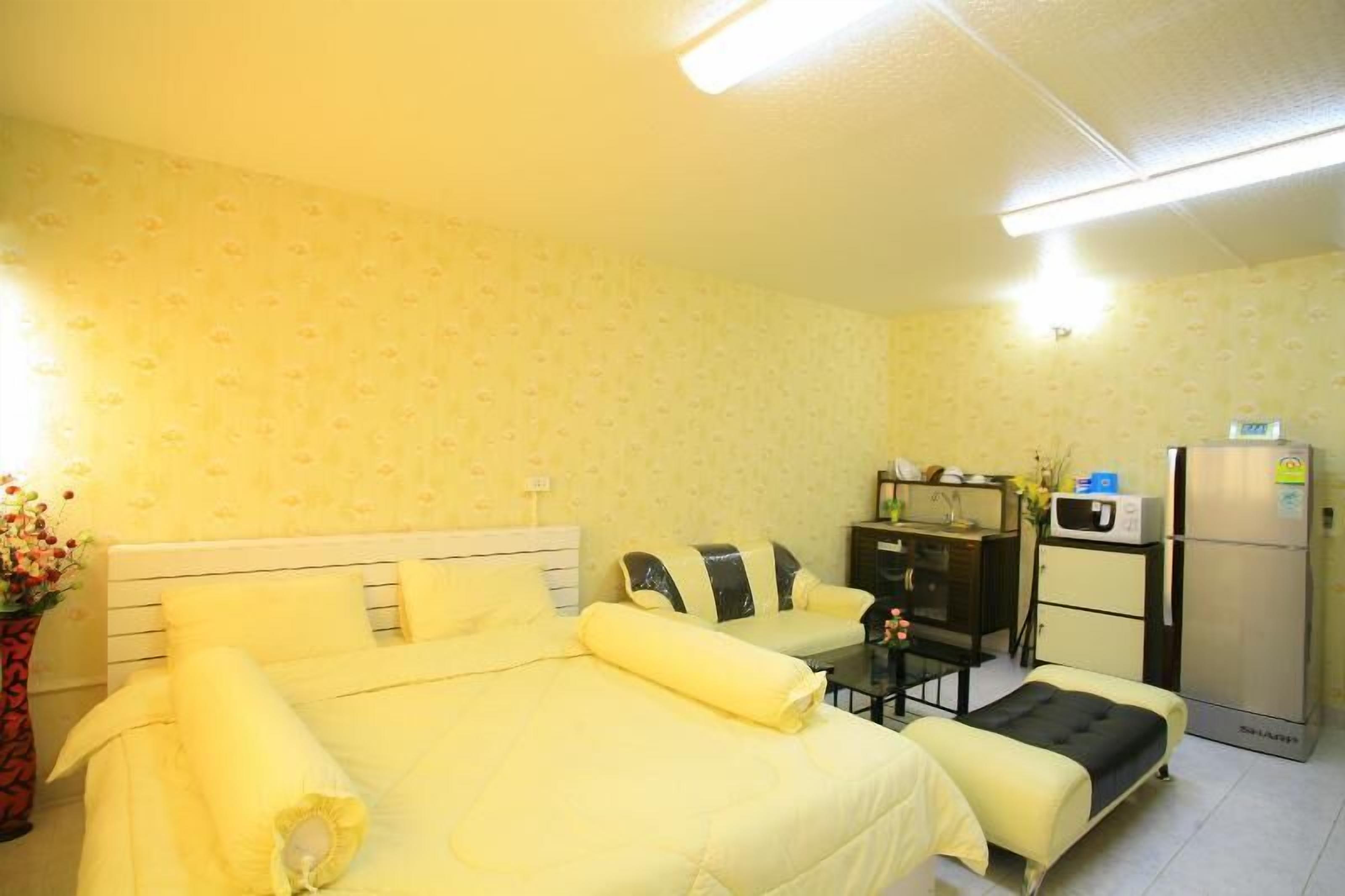 A hotel room with a large bed, a desk, a refrigerator, and a microwave.