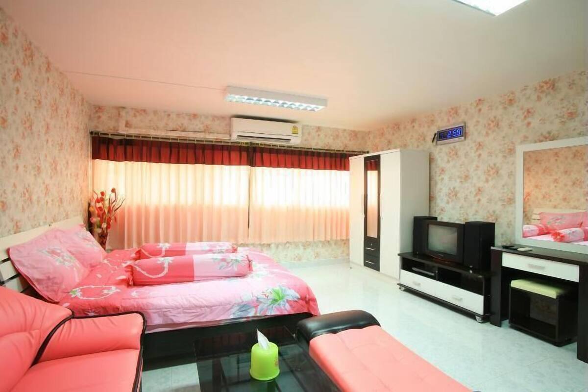 A hotel room with a bed, a desk with a television, and a mirror.