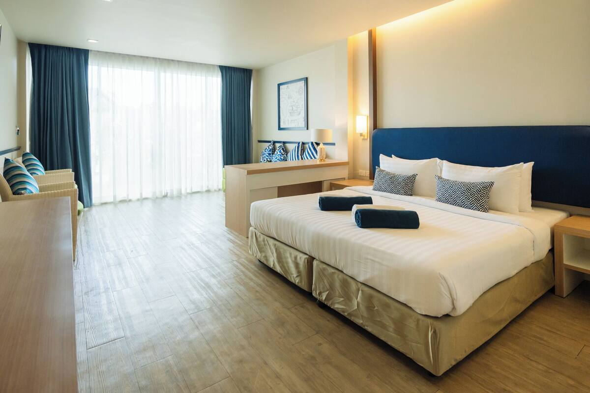 A hotel room with a large bed, a desk, and a chair.