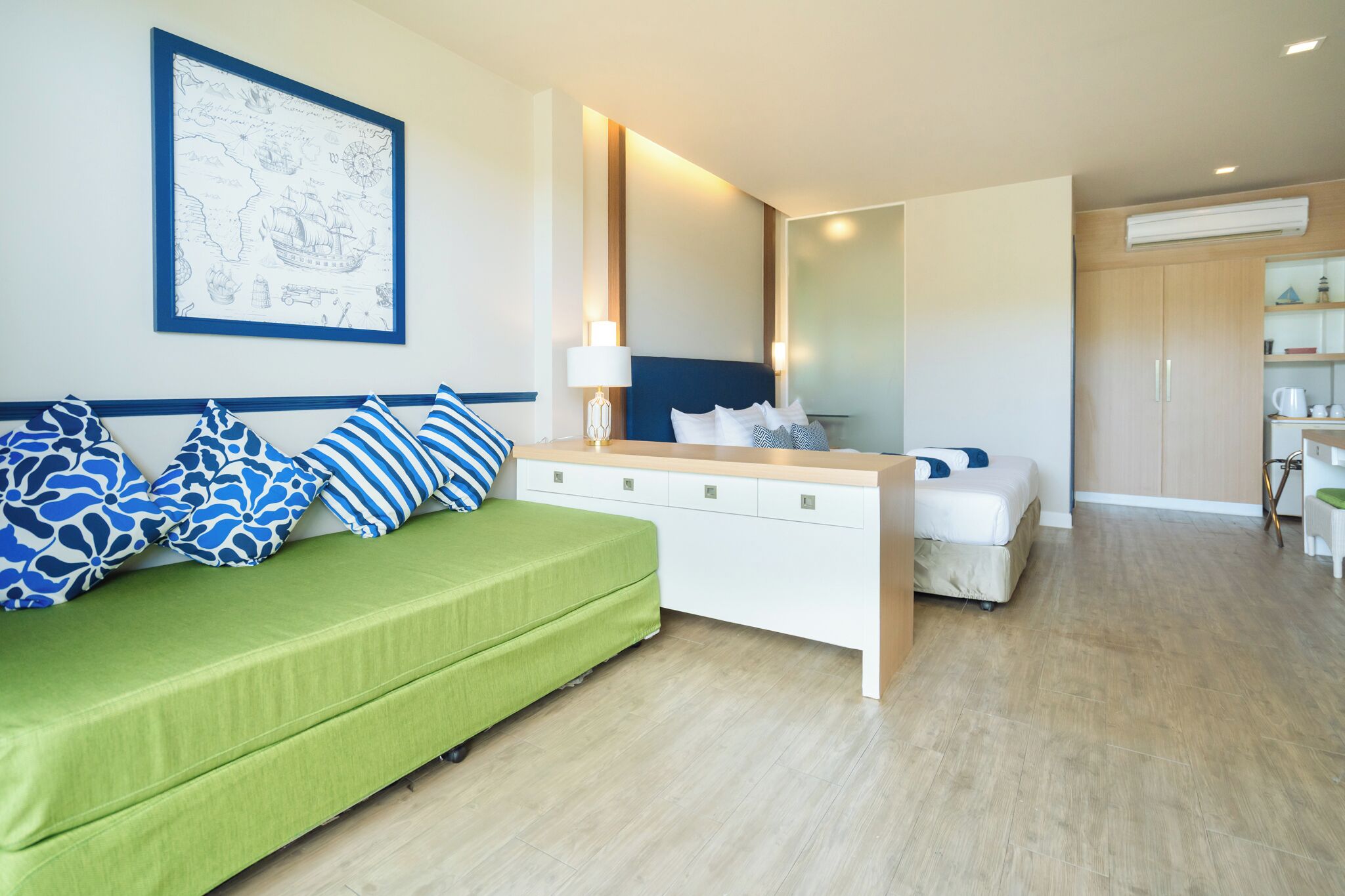 Una habitación de hotel moderna con un sofá verde, una mesita de noche blanca y una cama.