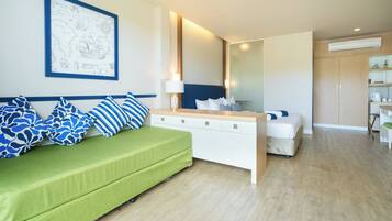 Una habitación de hotel moderna con un sofá verde, una mesita de noche blanca y una cama.