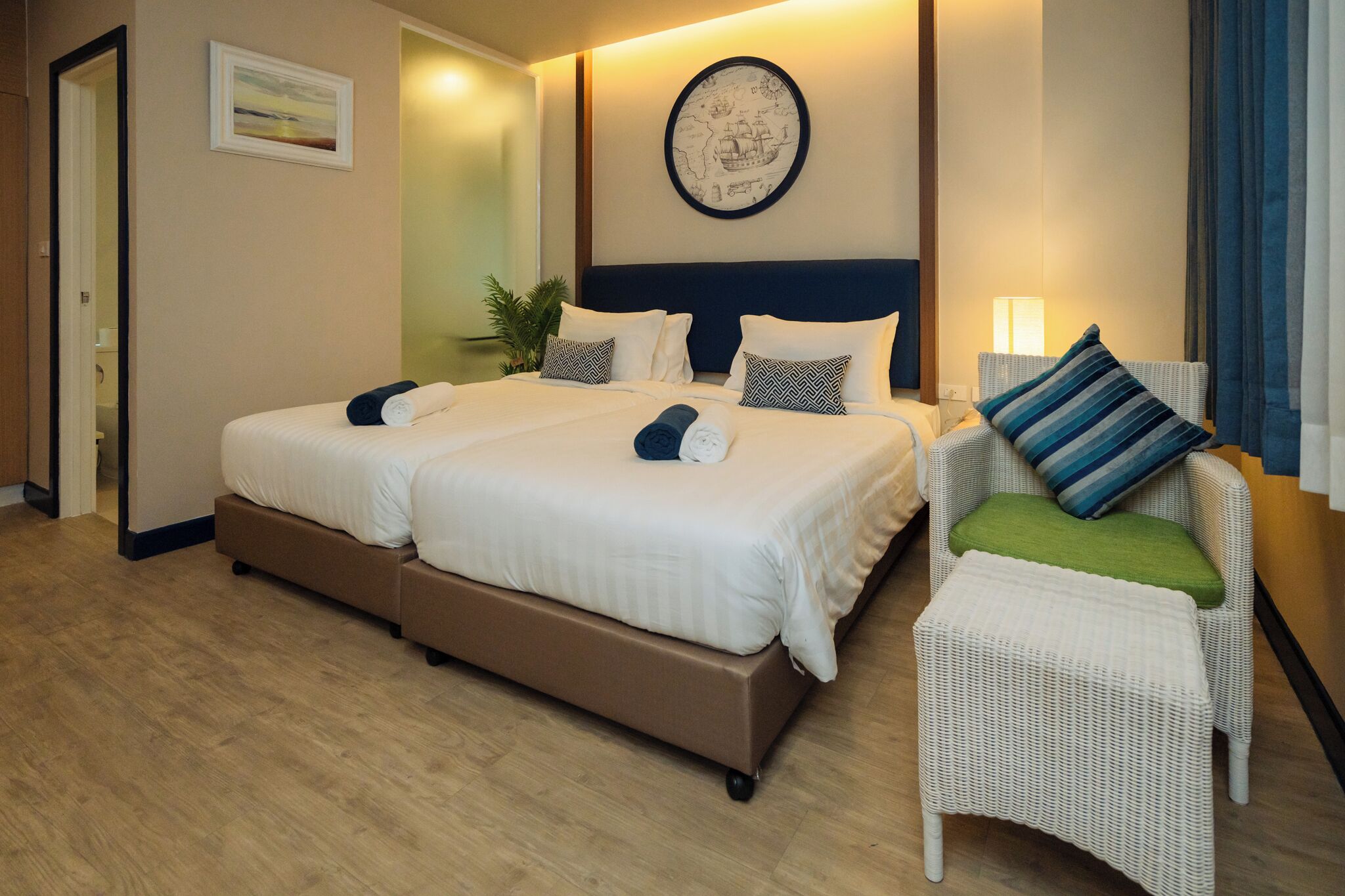 Quarto de hotel com uma cama grande, uma mesinha de cabeceira, uma cadeira e um mapa de parede.