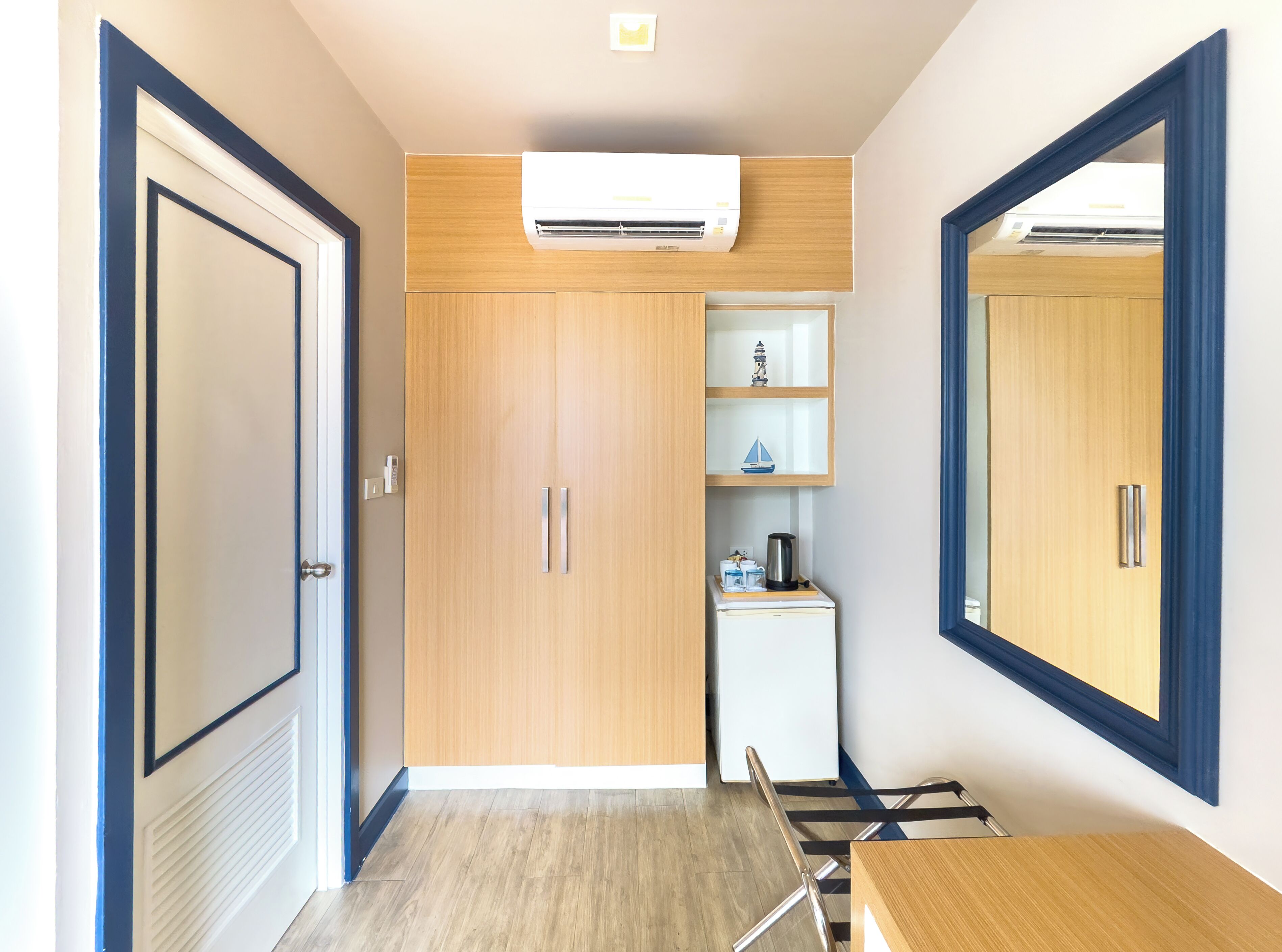 A compact kitchen with wooden cabinets, a built-in refrigerator, and a small shelf with decorative items.