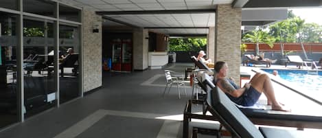 Un área junto a la piscina con sillones reclinables.