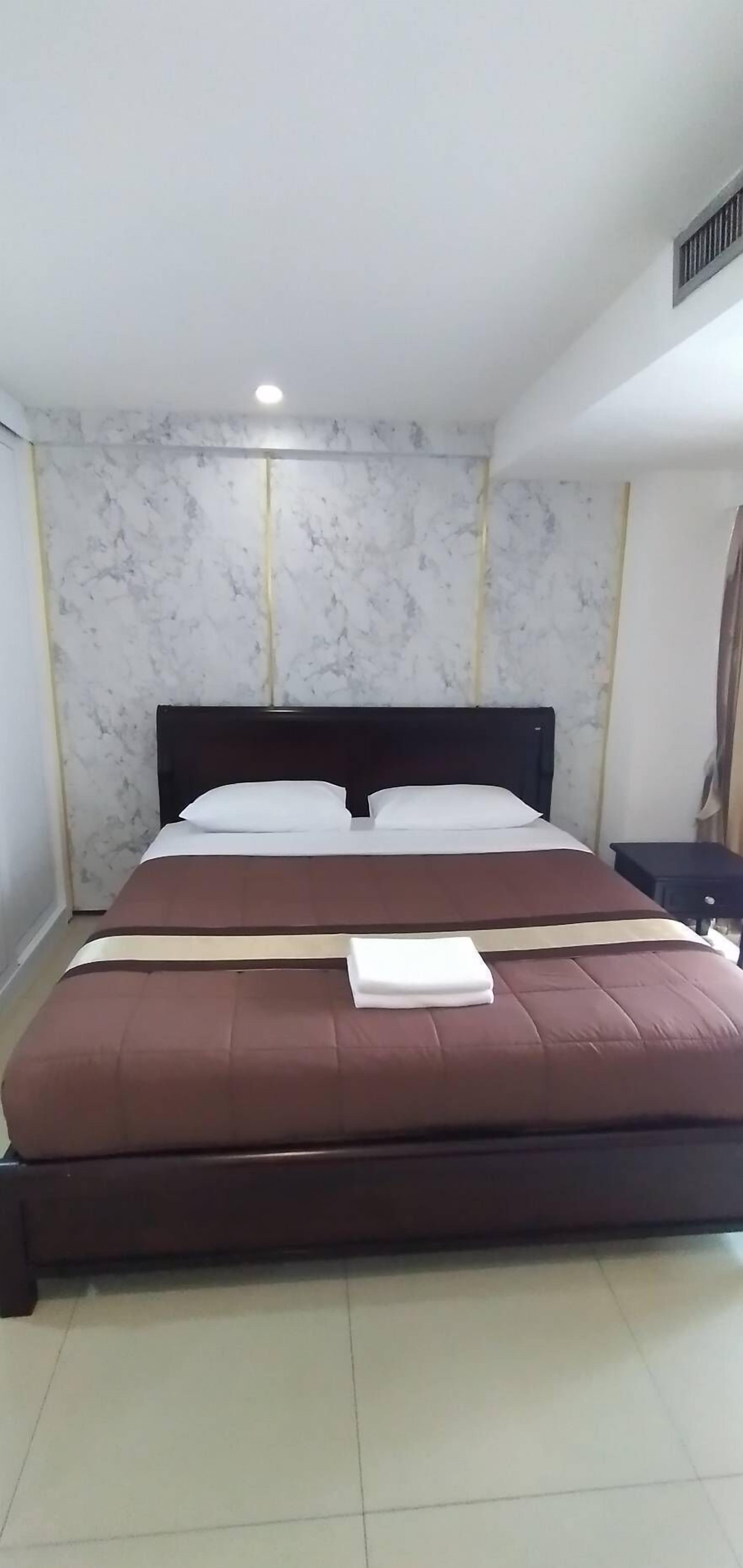 A neatly made bed with a dark headboard, white pillows, and a brown bedspread.